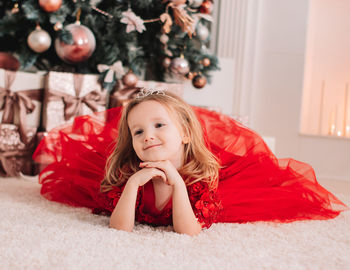 Portrait of smiling girl lying on christmas tree at home