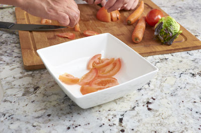 Close-up of hand holding food on cutting board