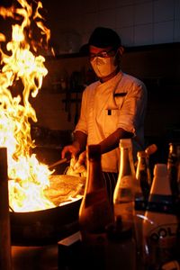 Rear view of man preparing food at night