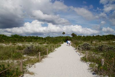 Rear view of woman walking on landscape against sky