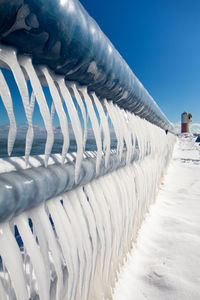 Snow covered land against clear blue sky