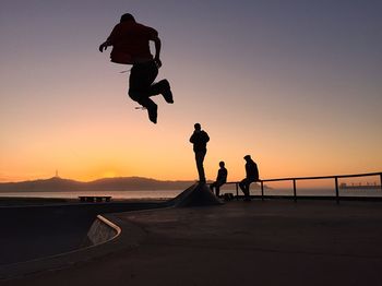 Silhouette man jumping against sky during sunset