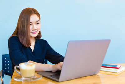 Young woman using mobile phone while sitting on table