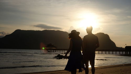 Silhouette people by sea against sky during sunset