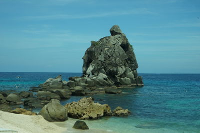 Rock formation on beach against sky