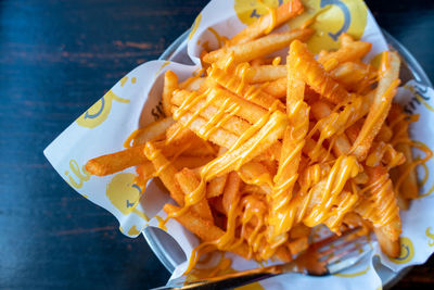 French fries topped with dipping sauce parchment paper