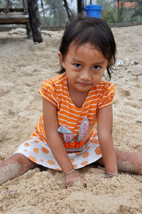 Portrait of cute girl sitting on sand