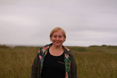 Portrait of smiling young woman standing on field