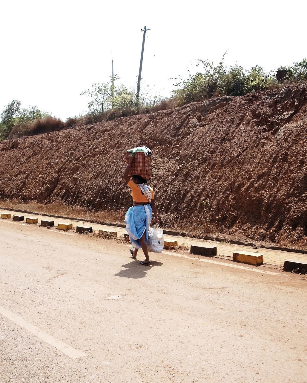 REAR VIEW OF MAN SKATEBOARDING ON ROAD