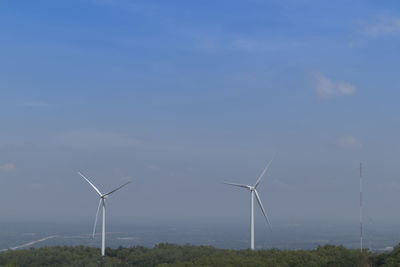 Wind turbines on field against sky