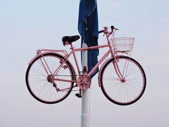 Bicycle hanging on pole against clear sky