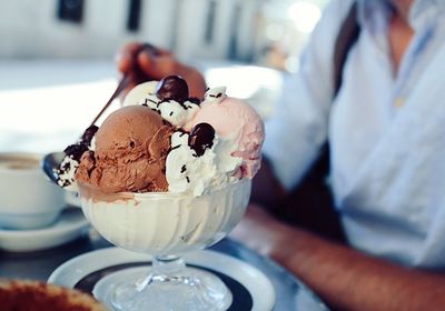 Midsection of man having ice cream at sidewalk cafe