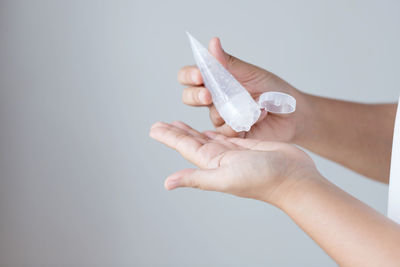 Close-up of woman holding hands over white background