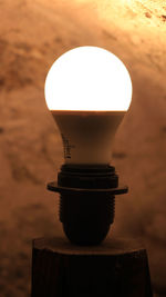 Close-up of illuminated lamp on table against wall