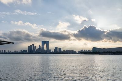 Sea by buildings against sky in city