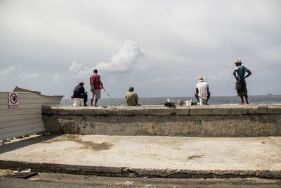 People looking at sea against sky