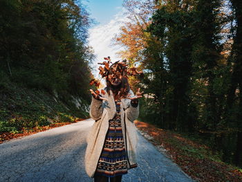 Woman standing on road amidst trees