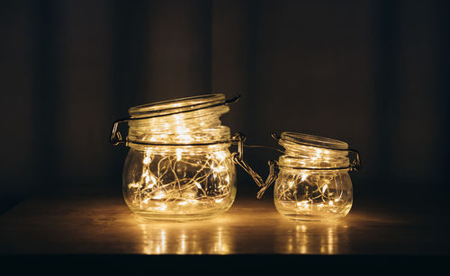 Close-up of fairy lights in glass jars on table