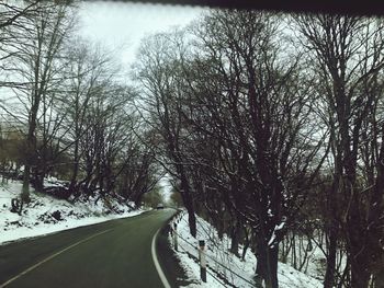 Road amidst bare trees during winter