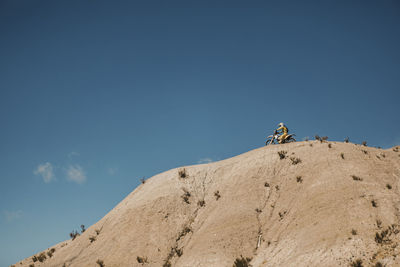 Rear view of people walking on mountain against clear blue sky