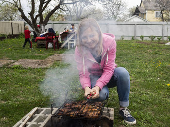 Portrait of woman preparing food on barbecue at lawn