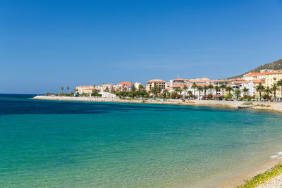 Scenic view of sea by buildings against blue sky