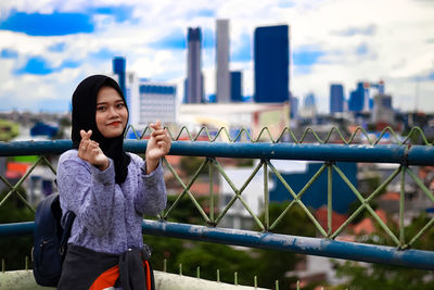 Full length of woman standing on railing against cityscape