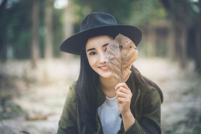 Portrait of young woman holding dry leaf