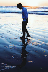 Full length of man standing on beach against sky