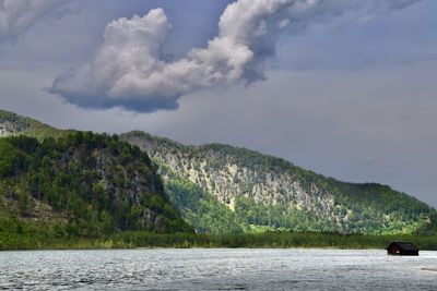 Scenic view of lake and mountains against cloudy sky