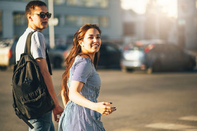 Portrait of smiling young woman walking with man on road