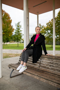 Full length of young woman sitting on bench outdoors