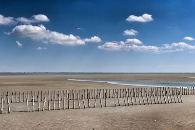 Wooden posts on beach against sky