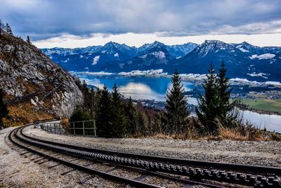 Railroad tracks by snowcapped mountains against sky