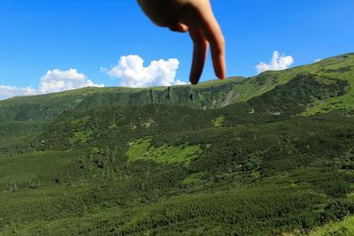 Optical illusion of person touching mountain against sky