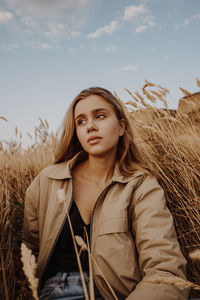 Portrait of young woman in field against sky