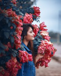 Low angle view of woman standing by red flowering plant