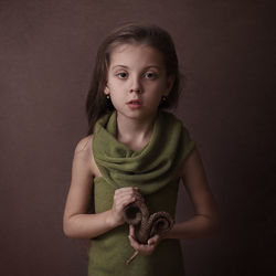 A girl on a brown background holds a palm leaf signifying the zodiac s