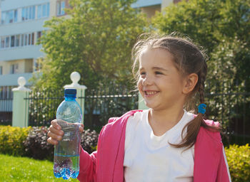 Smiling girl holding bottle at park