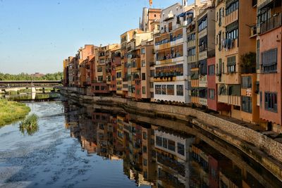 Buildings by canal against sky in city