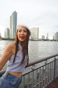 Smiling woman standing by railing against river