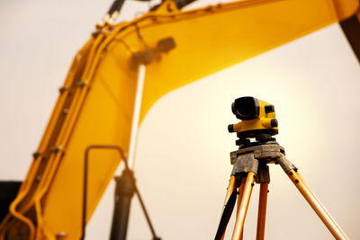 Close-up of theodolite and construction machinery against clear sky