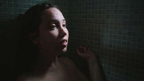 Close-up of young woman looking away while standing in bathroom