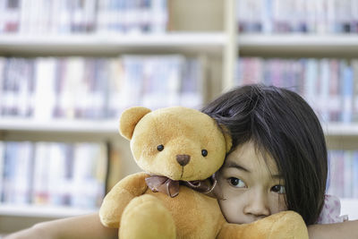 Girl with teddy bear in library