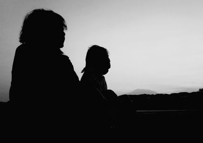 Silhouette man and woman standing against clear sky