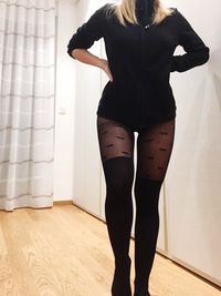 Rear view of woman standing against wall at home