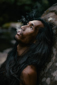 Man looking up while emitting smoke