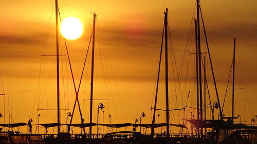 Sailboats moored on sea against sky during sunset