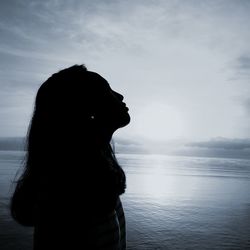 Silhouette woman looking at sea against sky