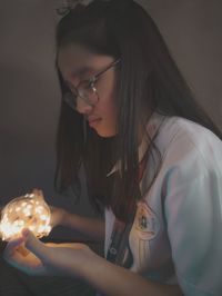 Young woman holding illuminated lighting equipment at home